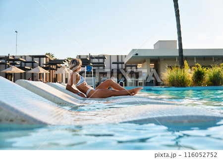 A girl sits near the pool after spa treatments. Turkey, hotel, vacation, travel, girl in a swimsuit 116052752