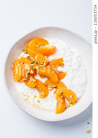 Breakfast cottage cheese with apricot, maple syrup and pistachio. 116053734