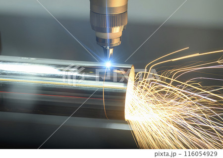 Close up scene the fiber laser cutting machine cut the stainless steel tube with sparkling light. 116054929
