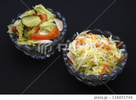 Vegetable salad in a glass salad bowl on a black background. A portion of vegetable salad. 116055748