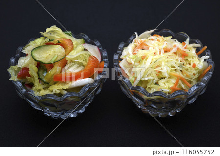 Vegetable salad in a glass salad bowl on a black background. A portion of vegetable salad. 116055752