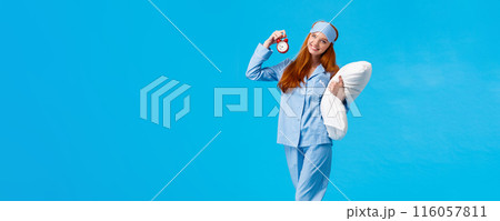 Time to bed. Vertical full-length cheerful lovely, gentle redhead european woman with long red hair, wearing nightwear and sleep mask, holding pillow and red alarm clock, sweet dreams Time to bed. Vertical full-length cheerful lovely, gentle redhead european woman with long red hair, wearing nightwear and sleep mask, holding pillow and red alarm clock, sweet dreams 116057811