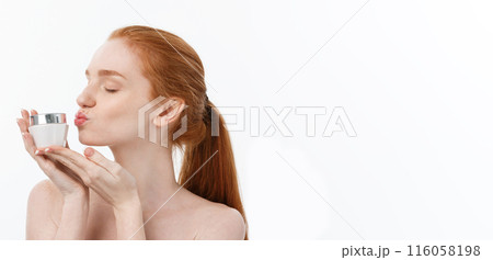 portrait of beautiful woman smiling while taking some facial cream isolated on white background with copy space. 116058198