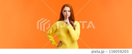 Serious and mad elder sister say keep silent, forbid talking during class, shushing angry with index finger pressed mouth, hold hand on waist in dissatisfied pose, standing orange background 116058203