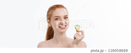 Close up beauty portrait of a smiling beautiful half naked woman holding cucumber slices at her face isolated over white background Close up beauty portrait of a smiling beautiful half naked woman holding cucumber slices at her face isolated over white background 116058689