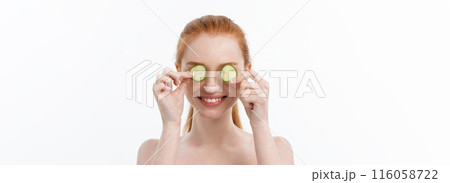 Close up beauty portrait of a smiling beautiful half naked woman holding cucumber slices at her face isolated over white background 116058722