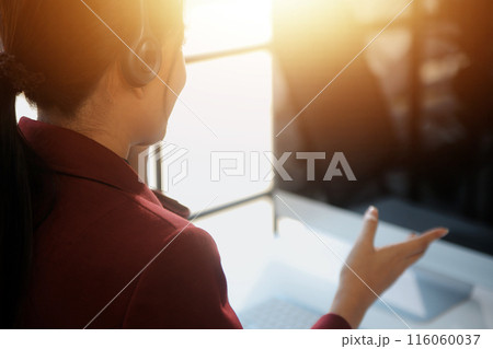 Friendly female helpline operator in call center. Young woman working in call center and holding microphone on headset with hand. 116060037