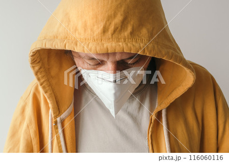 Casual male with yellow hooded jacket wearing protective respiratory KN95 face mask during covid-19 Casual male with yellow hooded jacket wearing protective respiratory KN95 face mask during covid-19 116060116
