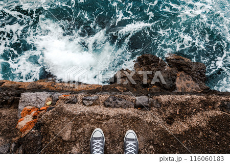 Suicidal ideation or thoughts, young person standing at the ocean cliff above the cold water and sea foam after waves crashing at rocks Suicidal ideation or thoughts, young person standing at the ocean cliff above the cold water and sea foam after waves crashing at rocks 116060183
