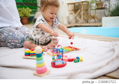 Happy baby playing with toys outdoors by the poolside Happy baby playing with toys outdoors by the poolside 116061721