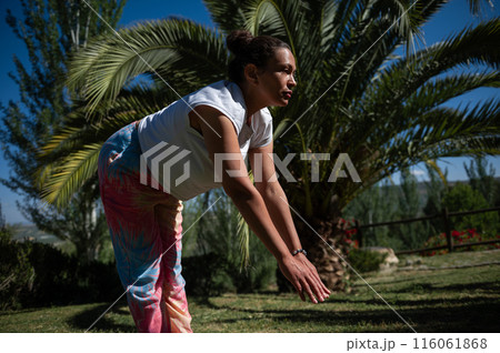 Woman doing yoga outdoors under palm tree in garden 116061868