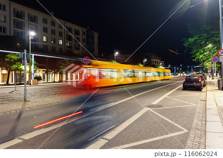 Scenic Dresden cityscape yellow tram motion blurred at dark night street with blurred cyclist and car parked along road. Germany Saxony capital city public transport commute Scenic Dresden cityscape yellow tram motion blurred at dark night street with blurred cyclist and car parked along road. Germany Saxony capital city public transport commute 116062024
