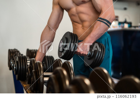 Close up sportsman lifting a dumbbell in the gym.  116062193