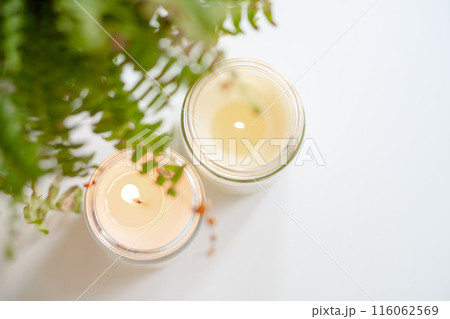 Scented candles with fern leaves on white background set tranquil mood for relaxation Scented candles with fern leaves on white background set tranquil mood for relaxation 116062569