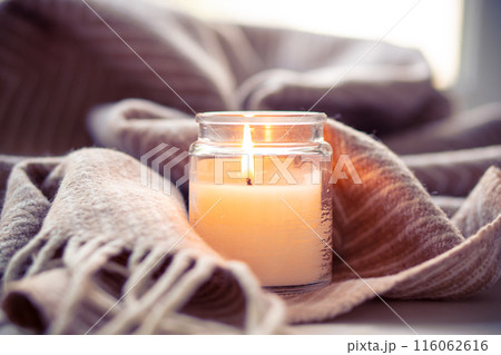 Cozy setting with candle and blanket, creating peaceful ambiance for winter relaxation Cozy setting with candle and blanket, creating peaceful ambiance for winter relaxation 116062616