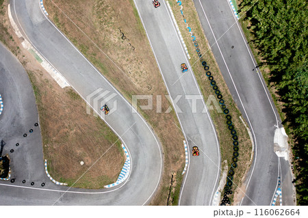 Motor vehicles racing around curve on race track Motor vehicles racing around curve on race track 116062664