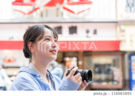 繫華街で趣味の写真撮影を楽しむ若くて可愛い女性イメージ｜女性カメラマンイメージ 116063893