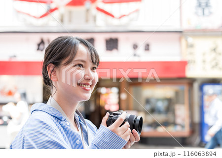 繫華街で趣味の写真撮影を楽しむ若くて可愛い女性イメージ｜女性カメラマンイメージ 116063894