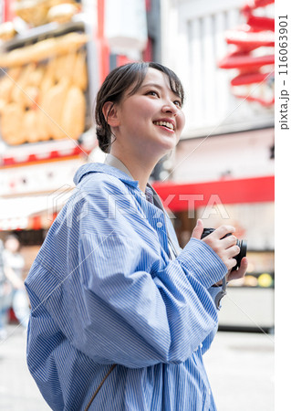 繫華街で趣味の写真撮影を楽しむ若くて可愛い女性イメージ｜女性カメラマンイメージ 116063901