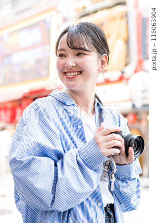繫華街で趣味の写真撮影を楽しむ若くて可愛い女性イメージ｜女性カメラマンイメージ 116063904