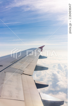 View from the airplane window at a beautiful cloudy sky and the airplane wing View from the airplane window at a beautiful cloudy sky and the airplane wing 116069647
