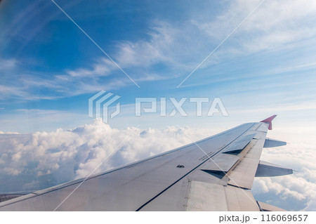 View from the airplane window at a beautiful cloudy sky and the airplane wing 116069657