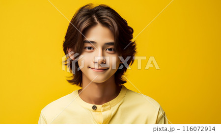 Portrait of a cute handsome happy Asian teenager guy with long hair and perfect skin, yellow background, banner. 116072914