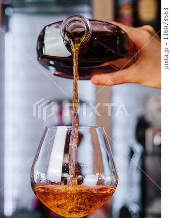 Pouring whiskey into glass at bar 116073563