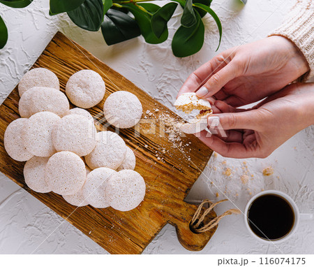 Hands breaking a fresh meringue cookie 116074175