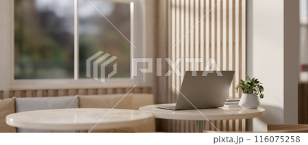 A back view image of a laptop computer on a table in a modern, comfortable cafe seating area. 116075258