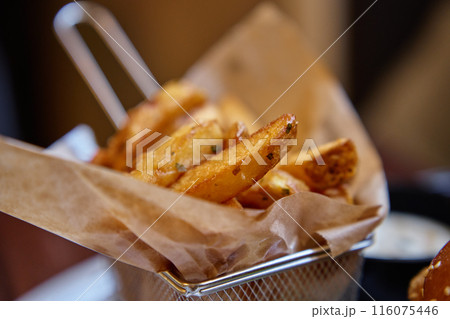Close-up shot of crispy French fries served in paper-lined basket in restaurant 116075446
