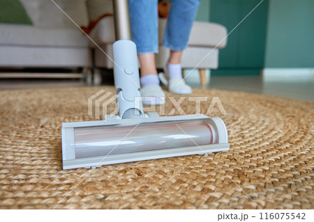 Close up of vacuum cleaner brush cleaning carpet on floor. Woman using portable cordless vacuum cleaner. Daily routine and household chores Close up of vacuum cleaner brush cleaning carpet on floor. Woman using portable cordless vacuum cleaner. Daily routine and household chores 116075542