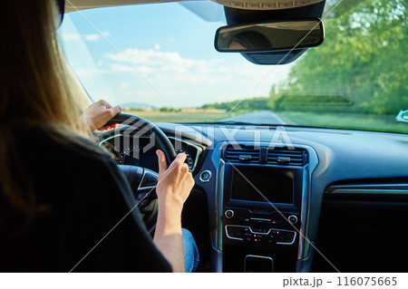 Woman driving car on country road at sunset. Back view of female driver in vehicle 116075665