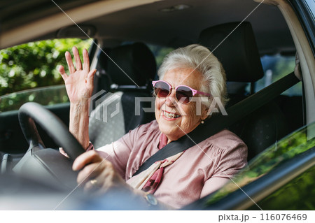 Happy senior woman driving car alone, enjoying car ride. Safe driving for elderly adults, older driver safety. 116076469