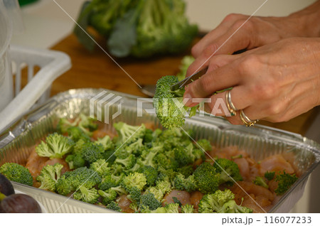 woman cutting broccoli into chicken fillet for baking 8 116077233