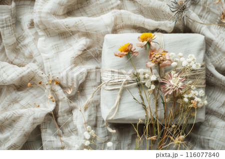 Sustainable gifting. Present wrapped in fabric, adorned with twine and dried flowers 116077840