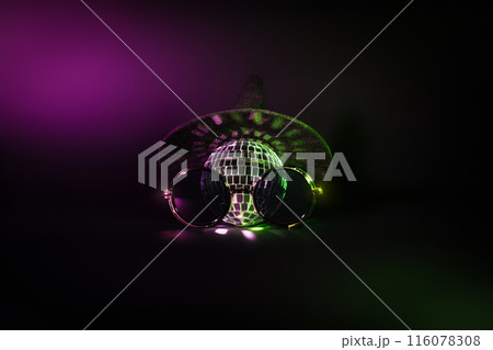A witch hat and a disco ball and hipster sunglasses with green and purple light on a black background. Creative Halloween party wallpaper A witch hat and a disco ball and hipster sunglasses with green and purple light on a black background. Creative Halloween party wallpaper 116078308