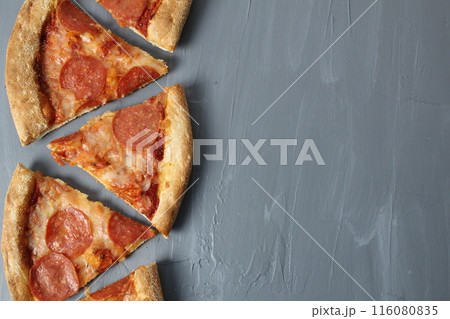 Border of pepperoni slices of pizza with cheese and sausage on a gray background with space for text Copyspace Upper angle Border of pepperoni slices of pizza with cheese and sausage on a gray background with space for text Copyspace Upper angle 116080835