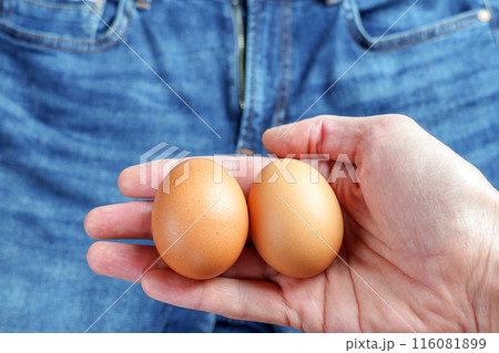 Two eggs in male hand on man jeans background. Infertility and urological diseases concept Two eggs in male hand on man jeans background. Infertility and urological diseases concept 116081899