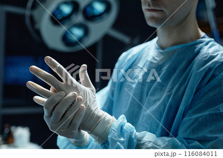 Cropped shot of surgeon wearing protective gloves preparing for surgery in operating room copy space 116084011