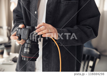Closeup of male photographer holding camera and looking at images during photoshoot in professional studio, copy space 116084298