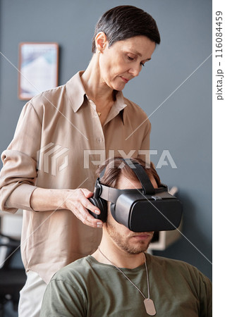 Minimal portrait of mature female psychologist using VR technology in therapy session for army veterans struggling with PTSD 116084459