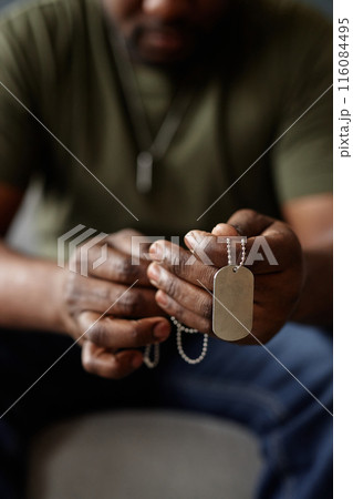 Vertical close up of unrecognizable Black man as army veteran holding dog tags in hands during therapy session 116084495