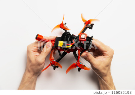 Male hands holding a high-speed racing fpv helicopter drone. Studio photo on a white background 116085198