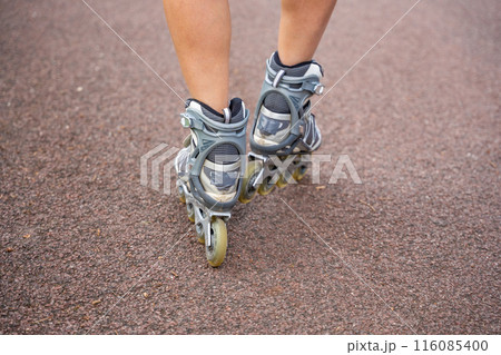 Close up view of feet in inline skates of roller skater woman. Rollerblading in park. Outdoor activities. Summer roller skating. Close up view of feet in inline skates of roller skater woman. Rollerblading in park. Outdoor activities. Summer roller skating. 116085400
