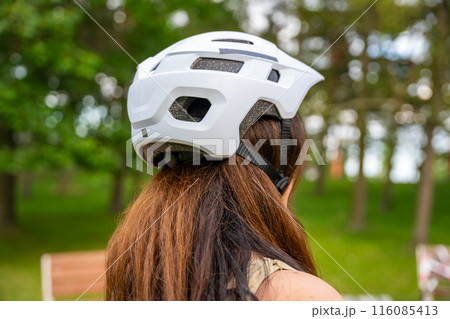 Portrait of roller skater woman putting on helmet in inline skates before rollerblading in park. Outdoor activities. Summer roller skating. 116085413