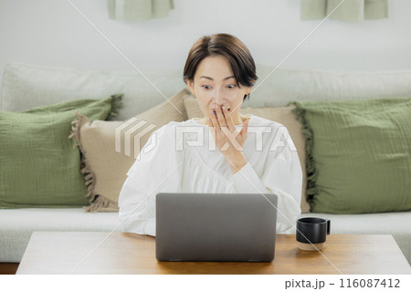 リビングでパソコンを見るミドルの女性 116087412