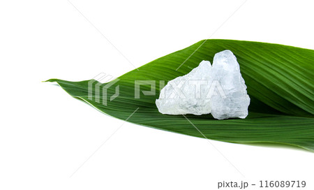 White crystal clear alum cube on green leaf isolated on white background. 116089719