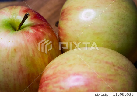 Fresh Apple Trio. Three apples on a wooden surface, embodying freshness and health. Fresh Apple Trio. Three apples on a wooden surface, embodying freshness and health. 116090039