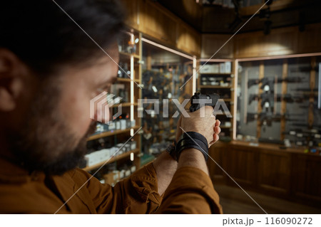 Man aiming gunpoint while choosing handgun in weapon shop, closeup view on gunpoint Man aiming gunpoint while choosing handgun in weapon shop, closeup view on gunpoint 116090272